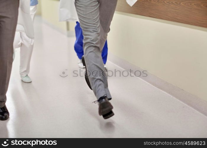 healthcare, people and medicine concept - close up of medics or doctors running along hospital corridor