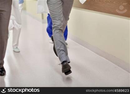 healthcare, people and medicine concept - close up of medics or doctors running along hospital corridor