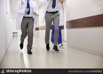 healthcare, people and medicine concept - close up of medics or doctors running along hospital corridor