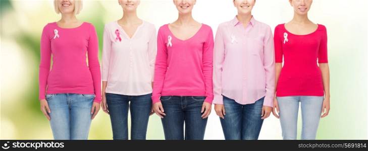 healthcare, people and medicine concept - close up of smiling women in blank shirts with pink breast cancer awareness ribbons over green background