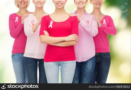 healthcare, people and medicine concept - close up of smiling women in blank shirts with pink breast cancer awareness ribbons over green background