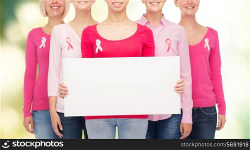 healthcare, people and medicine concept - close up of smiling women in shirts with pink breast cancer awareness ribbons and blank white board over green background
