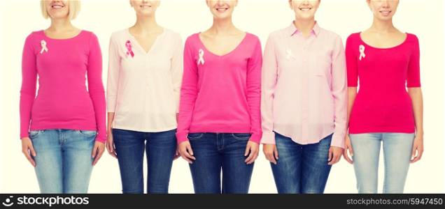 healthcare, people and medicine concept - close up of smiling women in blank shirts with pink breast cancer awareness ribbons over white background