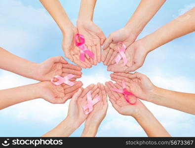 healthcare, people and medicine concept - close up of women hands with cancer awareness ribbons over blue sky background