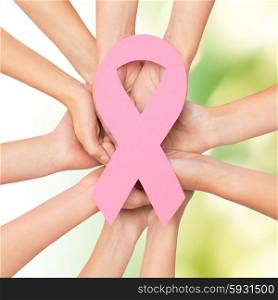 healthcare, people and medicine concept - close up of women hands with paper cancer awareness symbol over green background