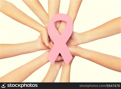healthcare, people and medicine concept - close up of women hands with paper cancer awareness symbol over white background