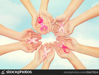 healthcare, people and medicine concept - close up of women hands with cancer awareness ribbons over blue sky background