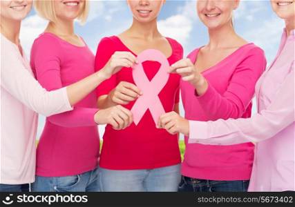 healthcare, people and medicine concept - close up of women in blank shirts with pink breast cancer awareness ribbon over blue sky background