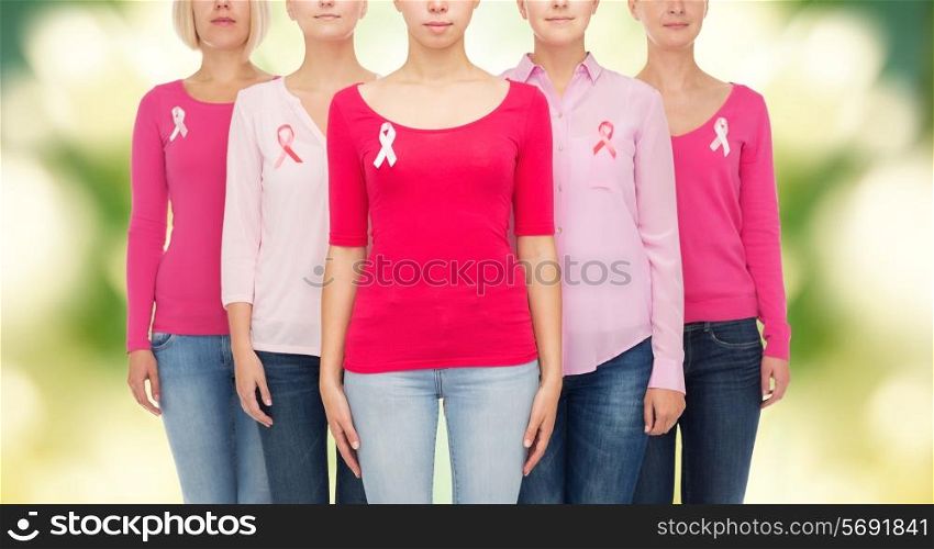 healthcare, people and medicine concept - close up of women in blank shirts with pink breast cancer awareness ribbons over green background