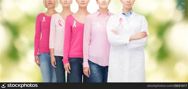 healthcare, people and medicine concept - close up of women in blank shirts with pink breast cancer awareness ribbons over green background