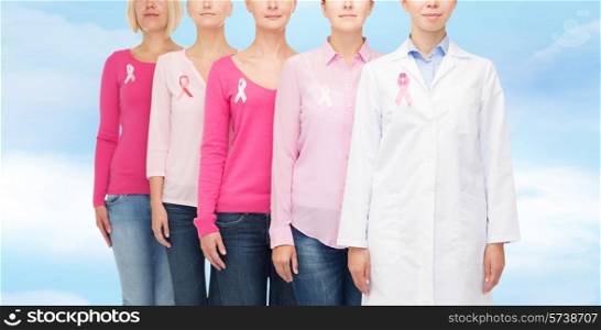 healthcare, people and medicine concept - close up of women in blank shirts with pink breast cancer awareness ribbons over blue sky background
