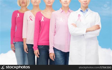 healthcare, people and medicine concept - close up of women in blank shirts with pink breast cancer awareness ribbons over blue sky and white cloud background