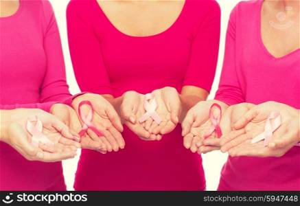 healthcare, people and medicine concept - close up of women in blank shirts with pink breast cancer awareness ribbons over white background