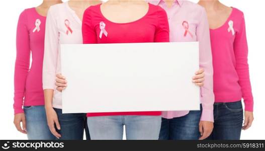 healthcare, people and medicine concept - close up of women in shirts with pink breast cancer awareness ribbons and blank white board over white background