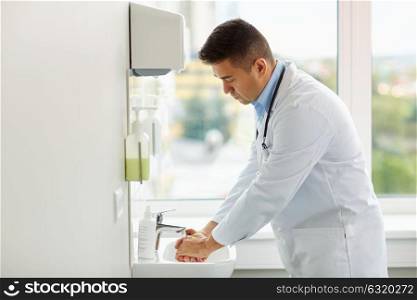healthcare, people and medicine concept - doctor washing hands at medical clinic sink. doctor washing hands at medical clinic sink