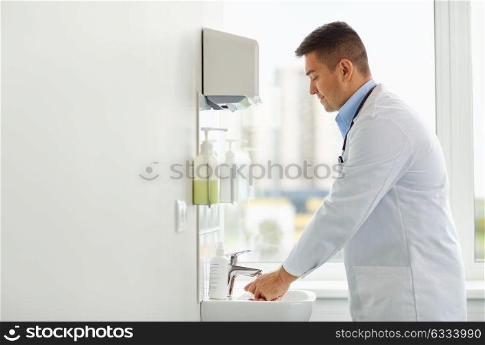 healthcare, people and medicine concept - doctor washing hands at medical clinic sink. doctor washing hands at medical clinic sink