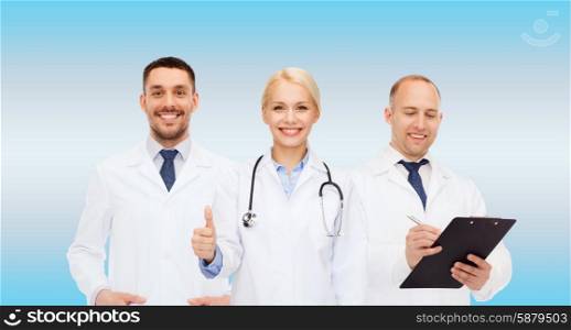 healthcare, people and medicine concept - group of doctors with stethoscope and clipboard showing thumbs up over blue background