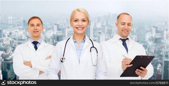 healthcare, people and medicine concept - group of doctors with stethoscopes and clipboard over city background