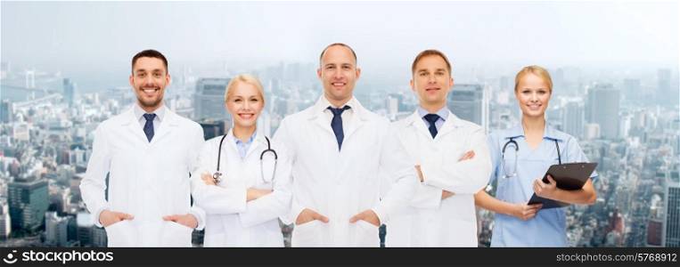 healthcare, people and medicine concept - group of doctors with stethoscopes and clipboard over city background