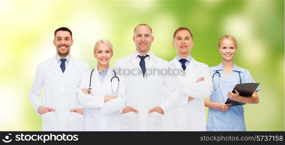 healthcare, people and medicine concept - group of doctors with stethoscopes and clipboard over green background