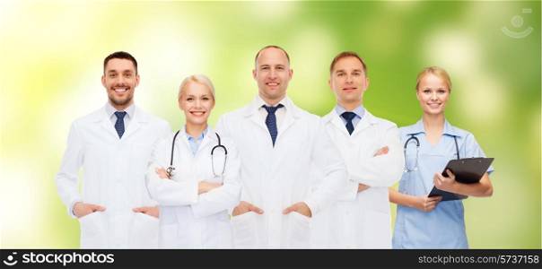 healthcare, people and medicine concept - group of doctors with stethoscopes and clipboard over green background
