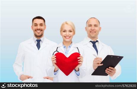 healthcare, people and medicine concept - group of smiling doctors with heart and clipboard over blue background