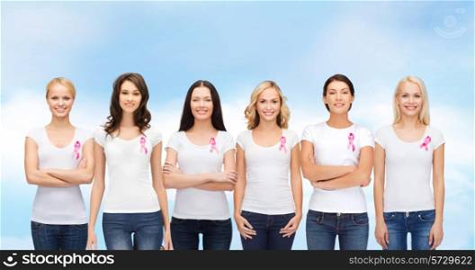healthcare, people and medicine concept - group of smiling women in blank t-shirts with pink breast cancer awareness ribbons blue sky background