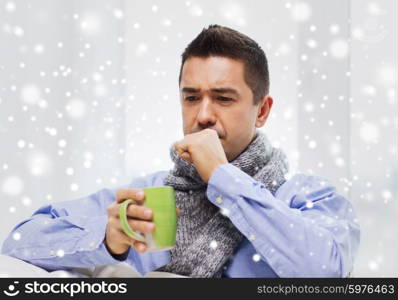 healthcare, people and medicine concept - ill man with flu coughing and drinking hot tea from cup at home over snow effect