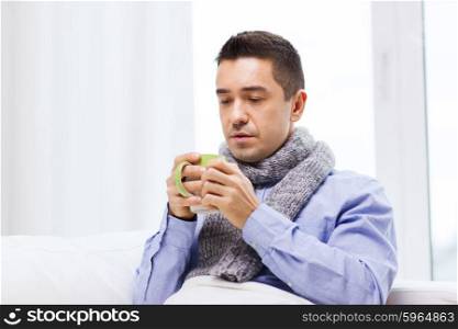 healthcare, people and medicine concept - ill man with flu drinking hot tea from cup at home