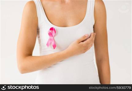 healthcare, people and medicine concept - sclose up of woman in white shirt with pink cancer awareness ribbon