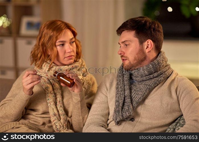 healthcare, people and medicine concept - sick couple with medication or antipyretic syrup and spoon at home. sick couple with medicine or antipyretic syrup
