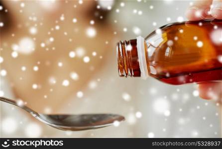 healthcare, people and medicine concept - woman pouring medication or antipyretic syrup from bottle to spoon over snow. woman pouring medication from bottle to spoon
