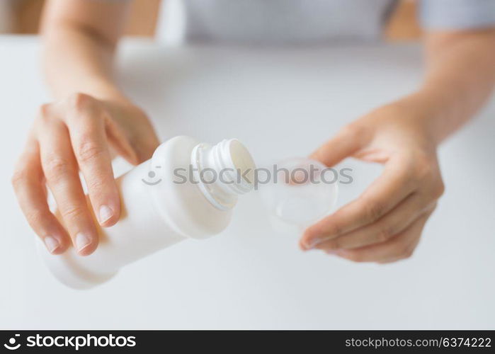 healthcare, people and medicine concept - woman pouring medication or antipyretic syrup from bottle to cup. woman pouring syrup from bottle to medicine cup