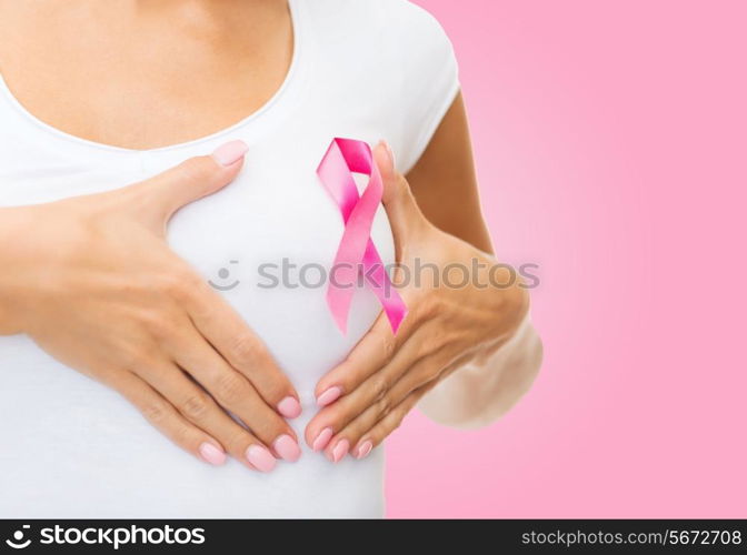 healthcare, people, charity and medicine concept - close up of woman in t-shirt with breast cancer awareness ribbon over pink background