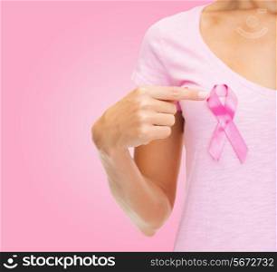 healthcare, people, charity and medicine concept - close up of woman in t-shirt with breast cancer awareness ribbon over pink background