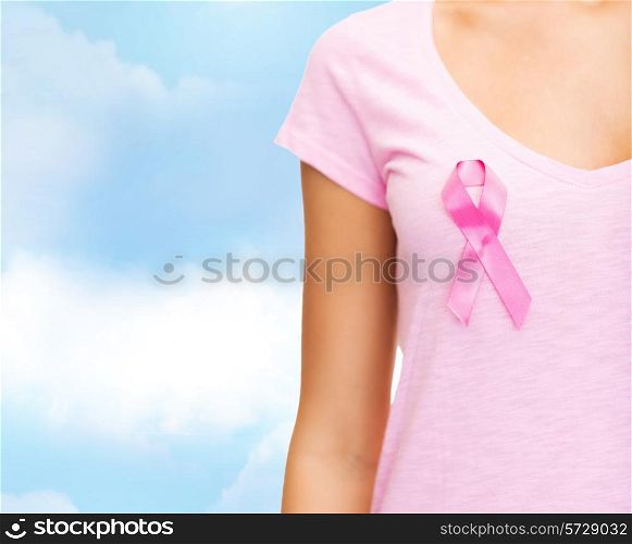 healthcare, people, charity and medicine concept - close up of woman in t-shirt with pink breast cancer awareness ribbon over blue sky background
