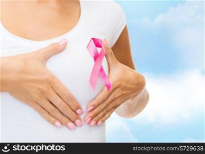 healthcare, people, charity and medicine concept - close up of woman in t-shirt with pink breast cancer awareness ribbon over blue sky background