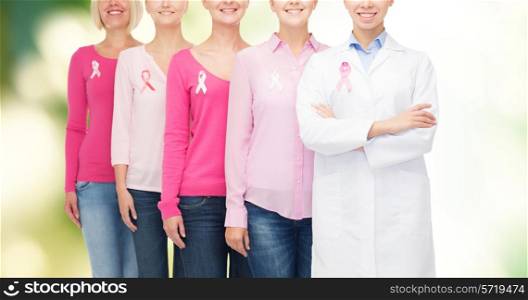 healthcare, people, eco and medicine concept - close up of smiling women in blank shirts with pink breast cancer awareness ribbons over green background