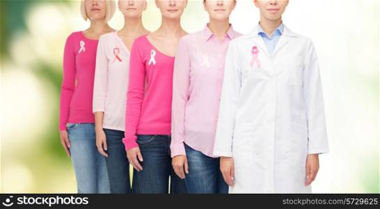 healthcare, people, eco and medicine concept - close up of women in blank shirts with pink breast cancer awareness ribbons over green background