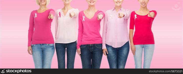 healthcare, people, gesture and medicine concept - close up of smiling women in blank shirts with breast cancer awareness ribbons pointing on you over pink background