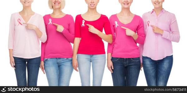 healthcare, people, gesture and medicine concept - close up of smiling women in blank shirts pointing fingers to pink breast cancer awareness ribbons over white background