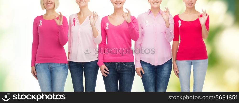 healthcare, people, gesture and medicine concept - close up of smiling women in blank shirts with pink breast cancer awareness ribbons showing ok sign over green background