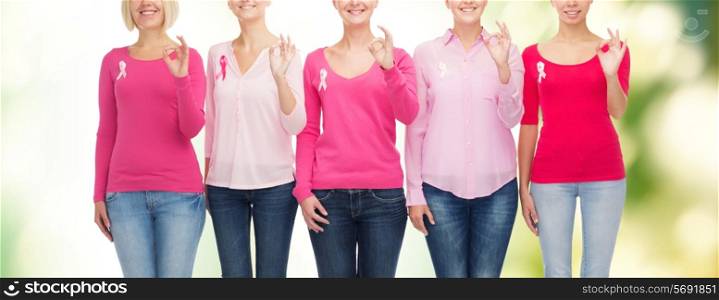 healthcare, people, gesture and medicine concept - close up of smiling women in blank shirts with pink breast cancer awareness ribbons showing ok sign over green background