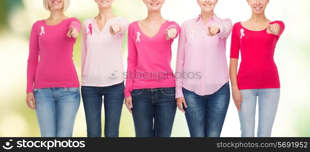 healthcare, people, gesture and medicine concept - close up of smiling women in blank shirts with pink breast cancer awareness ribbons pointing on you over green background