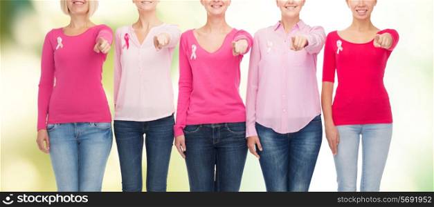 healthcare, people, gesture and medicine concept - close up of smiling women in blank shirts with pink breast cancer awareness ribbons pointing on you over green background