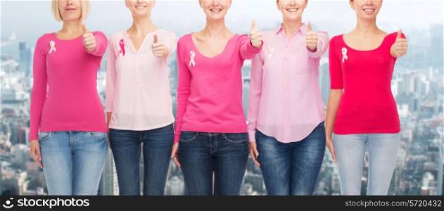 healthcare, people, gesture and medicine concept - close up of smiling women in blank shirts with pink breast cancer awareness ribbons over city background