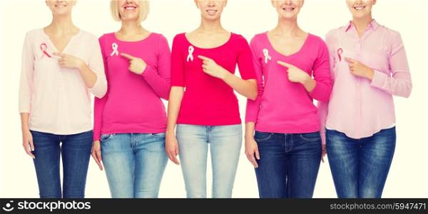 healthcare, people, gesture and medicine concept - close up of smiling women in blank shirts pointing fingers to pink breast cancer awareness ribbons over white background
