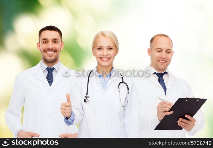 healthcare, people, gesture and medicine concept - group of doctors with stethoscope and clipboard showing thumbs up over green background