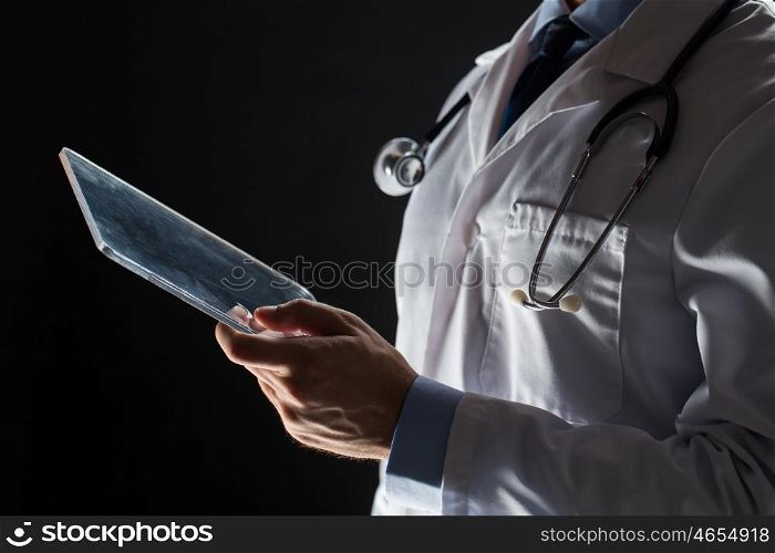 healthcare, people, technology and medicine concept - close up of male doctor in white coat with stethoscope and tablet pc computer over black background