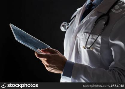 healthcare, people, technology and medicine concept - close up of male doctor in white coat with stethoscope and tablet pc computer over black background